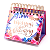 A Bloom brand, spiral ring, undated desktop calendar. Cover includes floral designs and This Year Is For Blooming text in gold cursive font.
