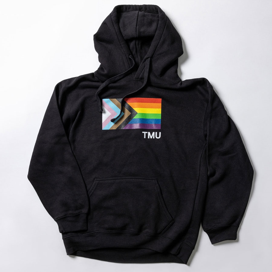 A black pullover fleece hoodie features the Pride Progress flag with a small right set TMU in white.