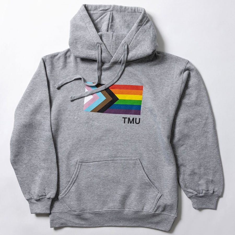 A heathered grey pullover fleece hoodie features the Pride Progress flag with a small right set TMU in white.